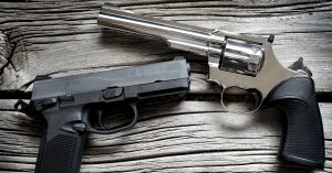 pistol and a revolver resting on a wooden table