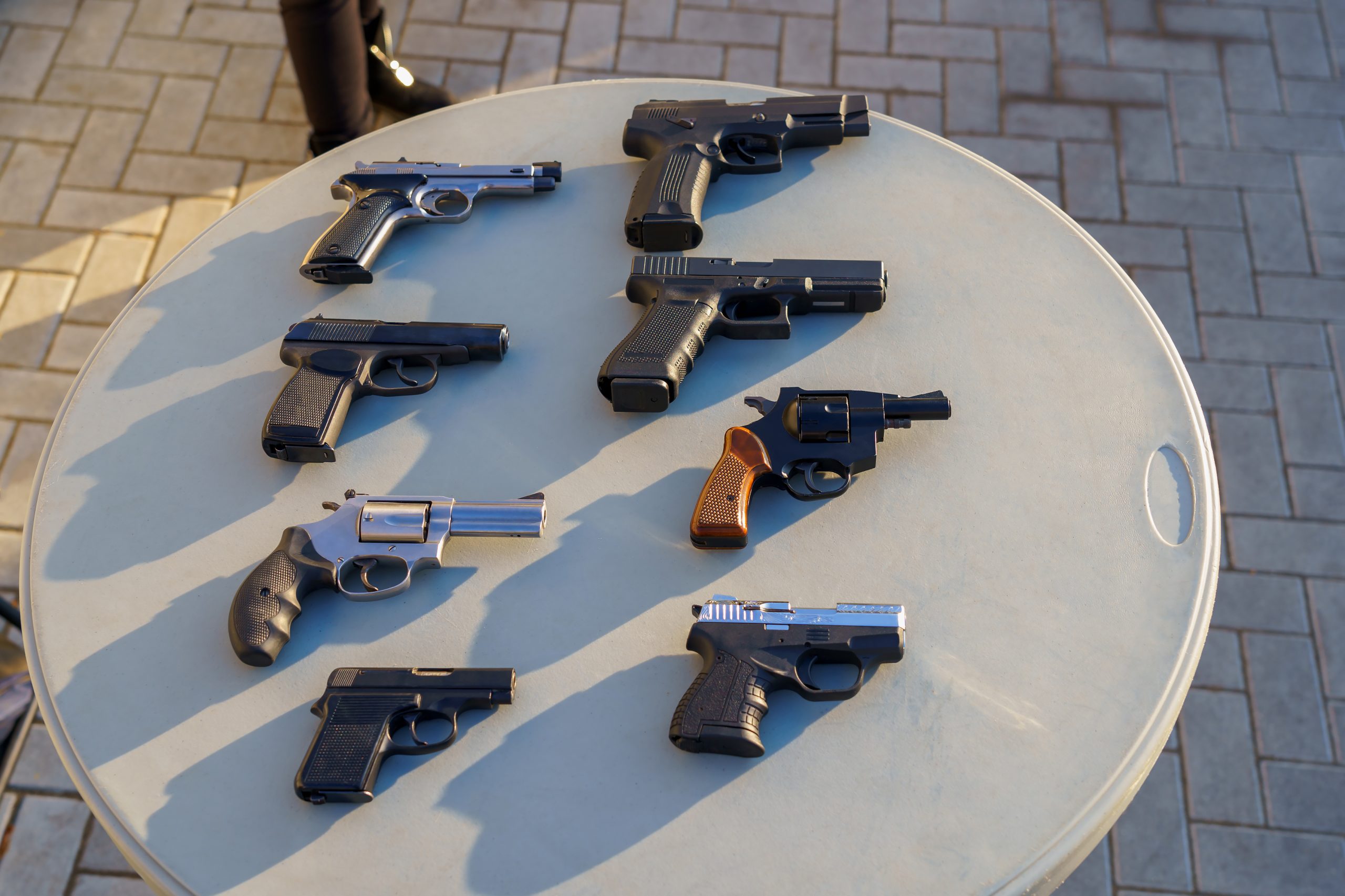 a selection of revolvers and pistols sitting on top of a plastic table