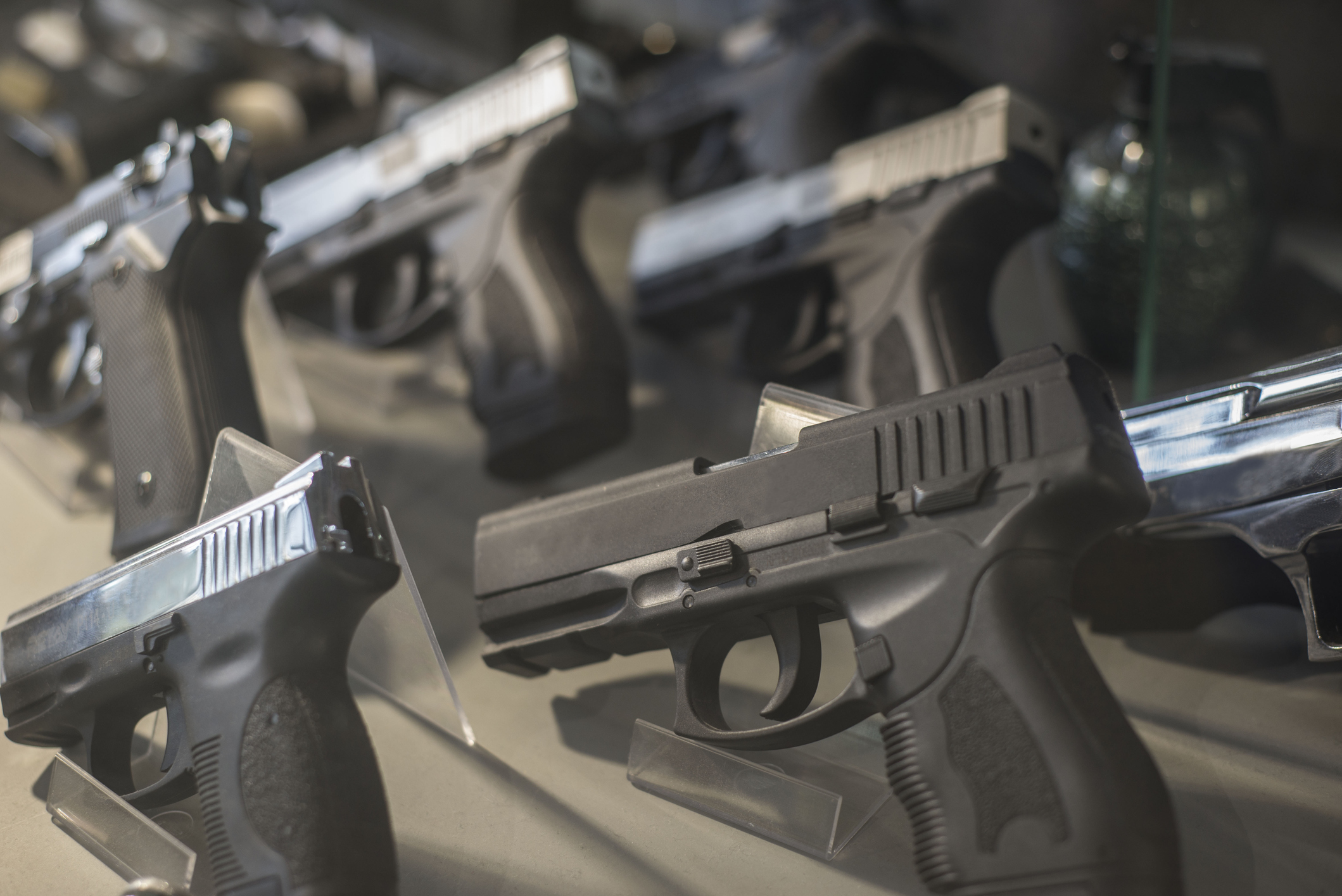Black pistols behind the glass of a local firearm store