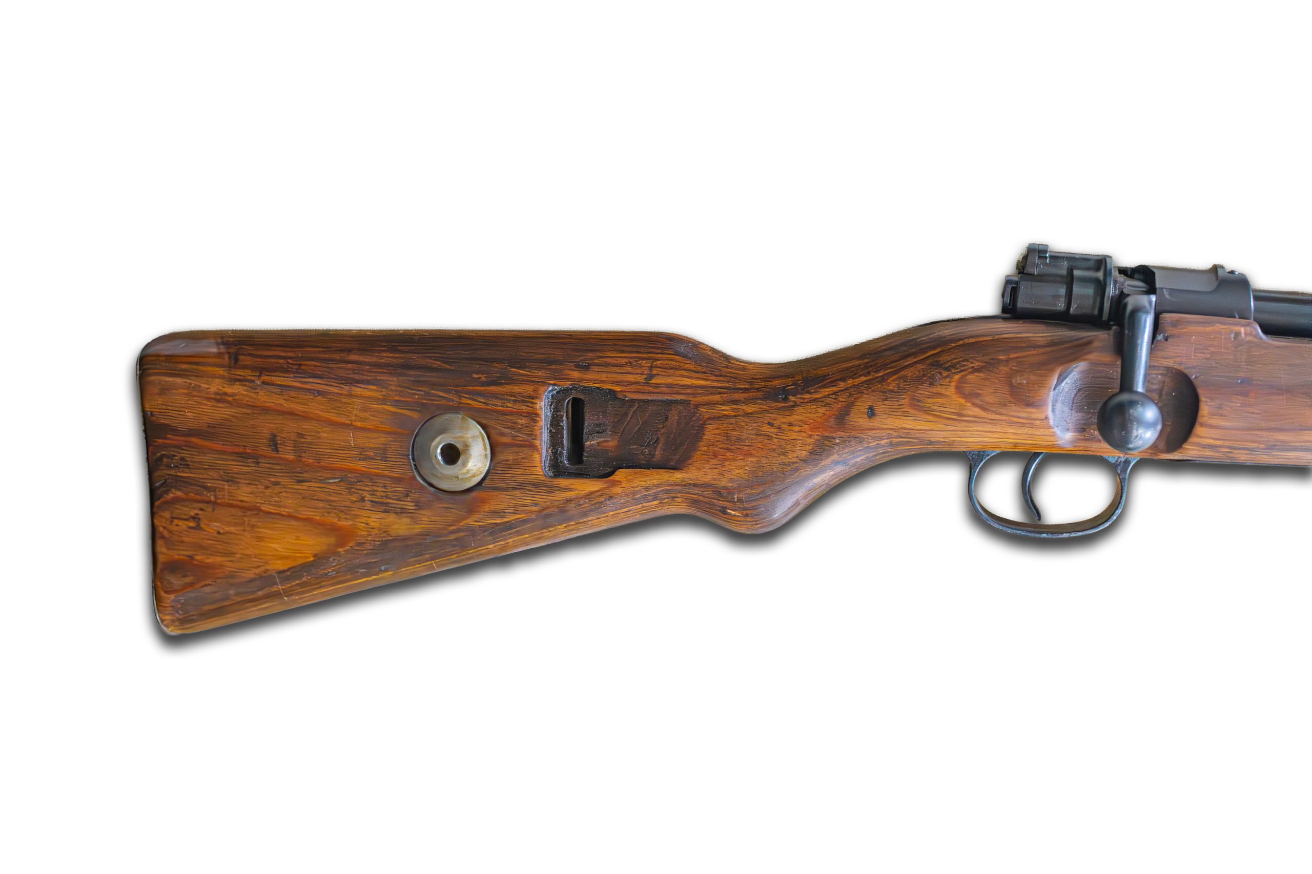 Close-up of a brown, wooden rifle with a black trigger and bolt action in soft, diffused lighting Indoor setting with neutral flooring No people present